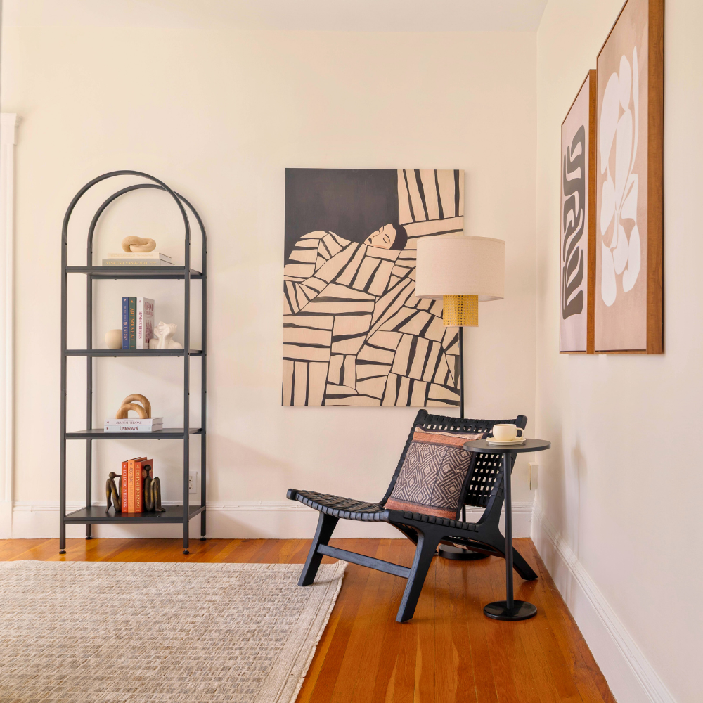 Modern interior with a black chair, round table, and wall art in a room with wooden flooring and a rug. Luxury staging in Cambridge, MA.